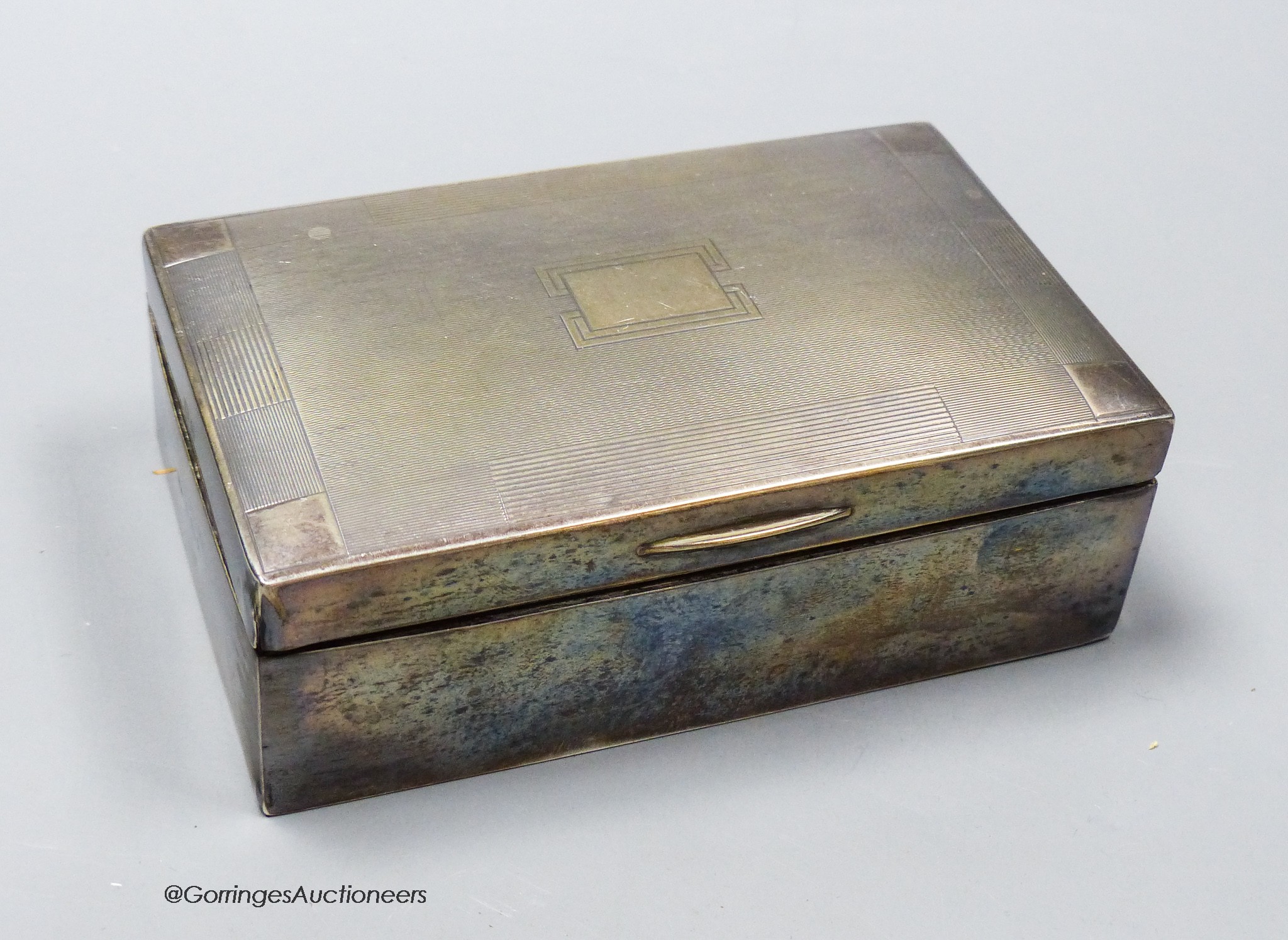 A George V silver mounted rectangular cigarette box, 13.7cm, a silver matchbox sleeve and a sterling cigar piercer.